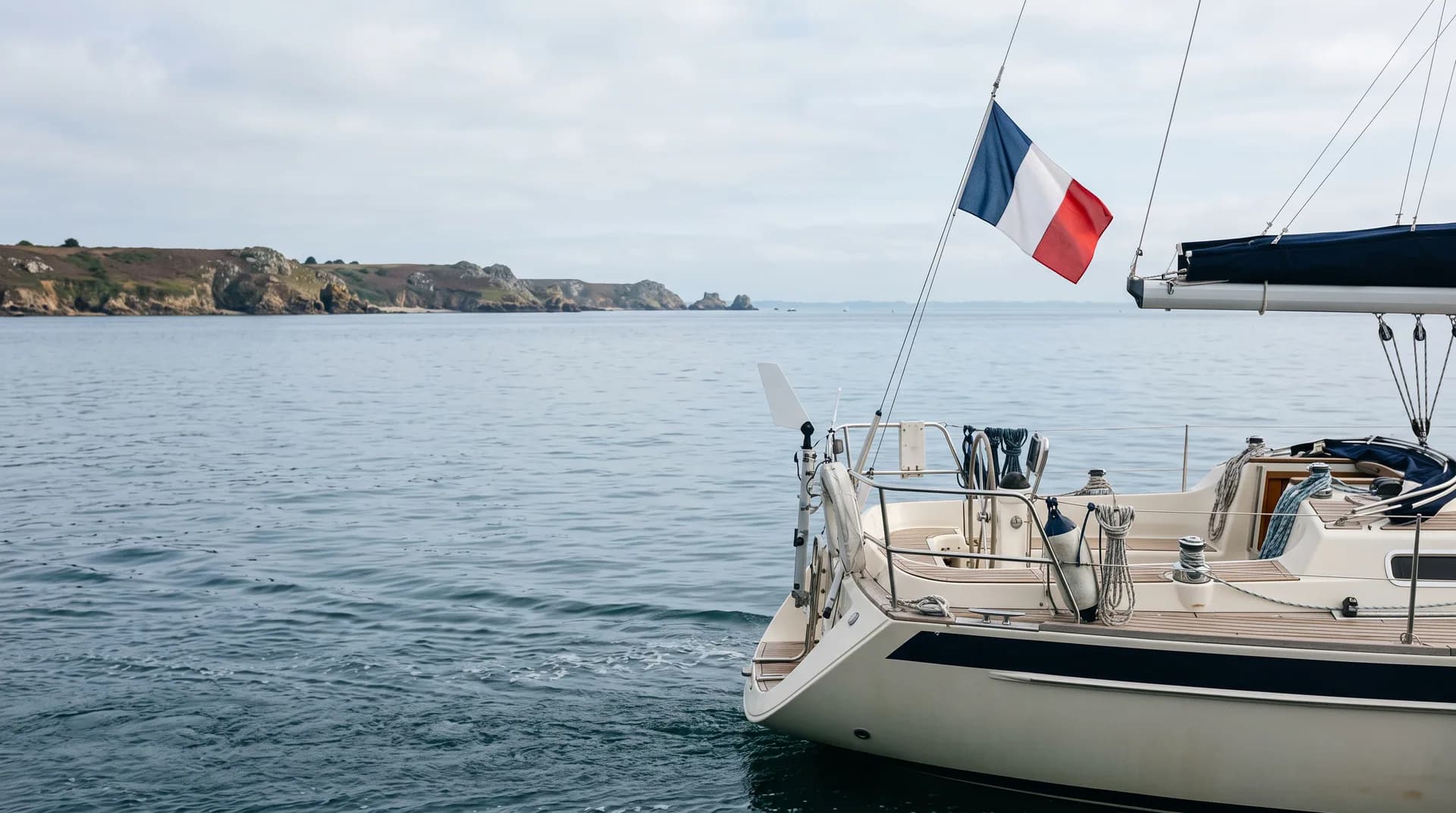 Pavillon national français hissé à la poupe d’un voilier naviguant près des côtes bretonnes